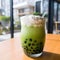 Bubble milk tea, Iced matcha latte with coffee tapioca pearls in transparent cup with drinking straw. Green tea with vegan milk,