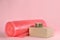 Bubble wrap roll, adhesive tape and cardboard box on pink background, space for text