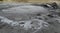 Bubbling crater of a mud volcano. Close up view onto gas bubble exploding in crater of mud volcano. Mud volcano at Paclele Mari,