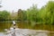 Bucharest, Romania - 1 May 2021: Man paddling on water and green weeping willow trees on the shoreline of Titan Lake in Alexandru