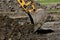 Bucket from a backhoe scrapes of a load of earth