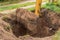 A bucket of a bulldozer with a pile of land next to a pit in an industrial zone. Excavation work