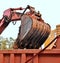 The bucket of the excavator filling sand in a truck body