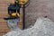 Bucket of the excavator on a heap of gravel against the background of a brick wall