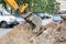 Bucket excavator in a pile of sand and asphalt debris