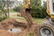 A bucket of excavator with a pile of sand and earth buries sewer concrete rings in the industrial zone