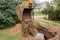 A bucket of excavator with a pile of sand and earth buries sewer concrete rings in the industrial zone