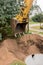 A bucket of excavator with a pile of sand and earth buries sewer concrete rings in the industrial zone