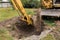 A bucket of excavator pours the ground into a heap against the background of a rural industrial zone. Bulldozer work on the