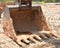 Bucket of excavator sits on ground