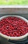 Bucket full of ripe red cranberries near window