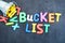 Bucket list concept, things to do in life with iron bucket and magnetic letters on chalkboard