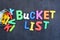 Bucket list concept, things to do in life with iron bucket and magnetic letters on chalkboard