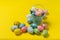 Bucket of multicolored festive eggs on yellow background. Happy Easter