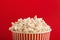 Bucket of popcorn on red background