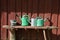 Bucket and three watering pots with red wooden wall background