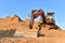 Bucket wheel excavator on earthmoving. Backhoe digs sand on blue sky background. Construction machinery for excavation, loading,