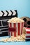 buckets of popcorn, clapperboard and film bobbin on blue, cinema concept.