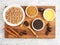 Buckwheat in ceramic bowl, nutmeg, cinnamon, star anise, fenugreek, oil on white concrete background