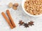 Buckwheat in ceramic bowl, nutmeg, cinnamon, star anise on white concrete background