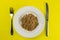 Buckwheat groats on a white plate isolated on yelllow background