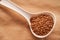 Buckwheat lies in a white plastic spoon on a brown background. close up