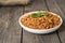 Buckwheat porridge with a sprig of parsley in a bowl, with a glass of milk and tomatoes on a dark rough wooden table. traditional