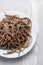 Buckwheat spaghetti on white plate on ceramic background