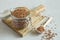 Buckwheat uncooked grains in glass jar on the wooden cutting board on gray background close up. Wooden spoon with grits.