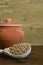 Buckwheat in a wooden spoon, next to a clay pot on a brown wooden background.