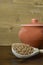 Buckwheat in a wooden spoon, next to a clay pot on a brown wooden background.