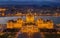 Budapest, Hungary - Aerial view of the illuminated Hungarian Parliament building at golden hour with Christmas tree and Buda Hills