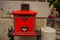 Budapest, Hungary. Bright red mailbox with a slot for letters, with a relief image of the mail horn, with legs supports
