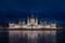 Budapest, Hungary - Illuminated Hungarian Parliament building with blue cloudy sky and reflection on River Danube