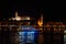 Budapest night landscape with lots of lanterns and illuminated buildings. A pleasure boat is sailing on the river