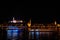 Budapest night landscape with lots of lanterns and illuminated buildings. A pleasure boat is sailing on the river