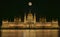 Budapest Parliament Building illuminated at night with dark sky and giant full moon