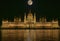 Budapest Parliament Building illuminated at night with dark sky and giant full moon