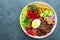 Buddha bowl dish with boiled egg, chickpea, fresh tomato, sweet pepper, cucumber, savoy cabbage, red onion, green sprouts, spinach