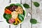 Buddha bowl with quinoa, hummus, mixed vegetables, over white wood