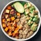 Buddha bowl with quinoa, tofu, avocado, sweet potato, brussels sprouts and tahini dressing, top view