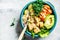 Buddha bowl with quinoa, tofu, avocado, sweet potato, brussels sprouts and tahini dressing, top view. Healthy vegan food concept