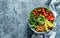 Buddha bowl salad with baked sweet potatoes, chickpeas, broccoli, tomatoes, greens, avocado, pea sprouts on light blue background