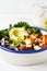 Buddha bowl salad with black rice, avocado, tofu, sweet potato, kale and tahini dressing, white background