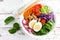 Buddha bowl salad with chickpeas, sweet pepper, tomato, cucumber, red cabbage kale, fresh radish, spinach leaves and boiled egg