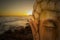 Buddha figure meditating with a sunrise on the beach