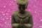 Buddha figure with pink diamonds in the background