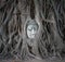 Buddha head in tree roots at Wat Mahathat, Ayutthaya, Thailand.