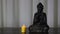 Buddha statue with candle burning by its side