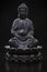 Buddha statue in lotus pose on black background.